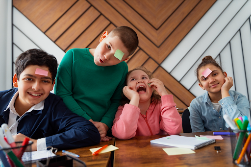 Children happily engaging in a playful activity with colorful sticky notes, promoting creativity and collaborative learning.
